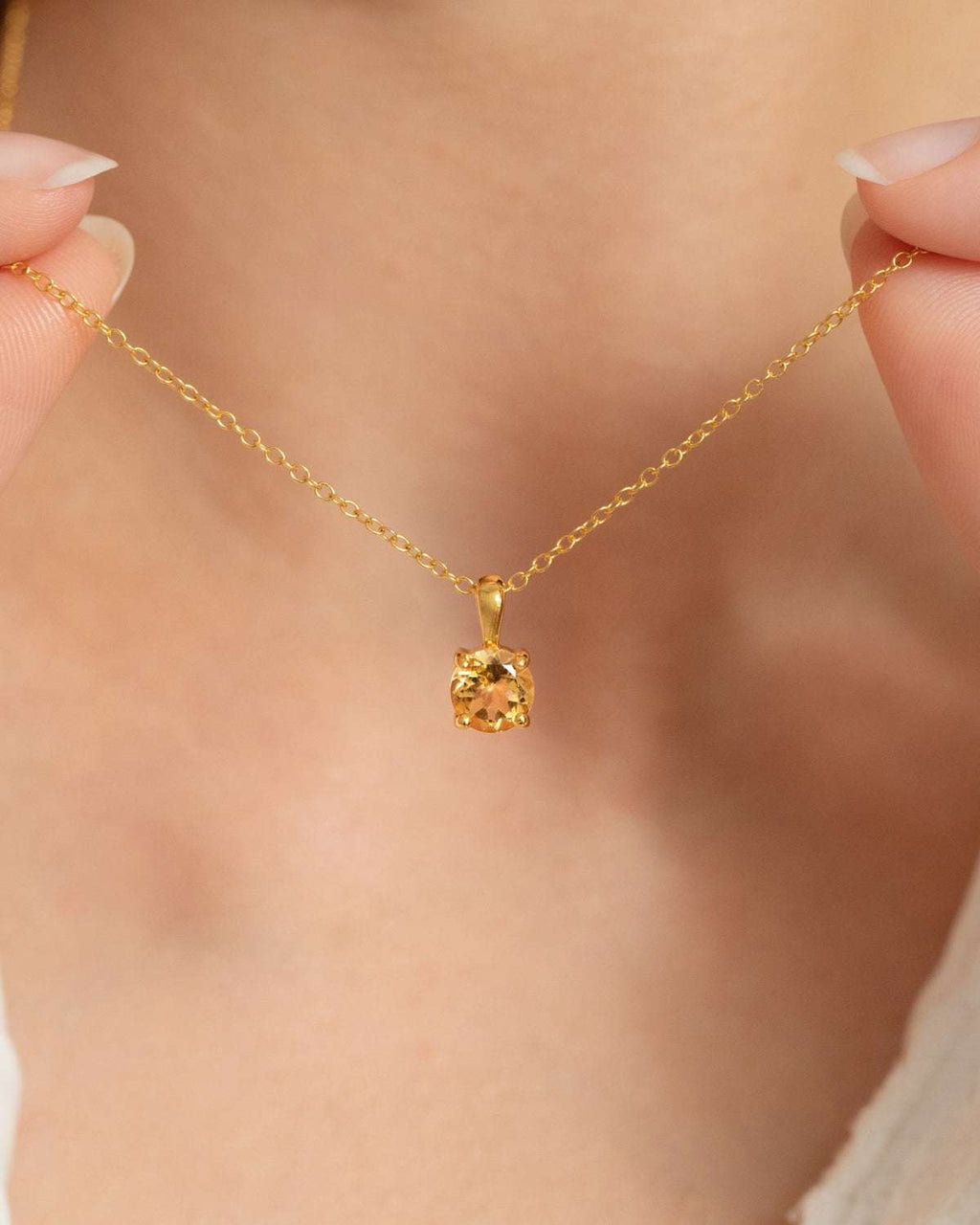 Citrine solitaire pendant necklace with a faceted round gemstone and gold chain