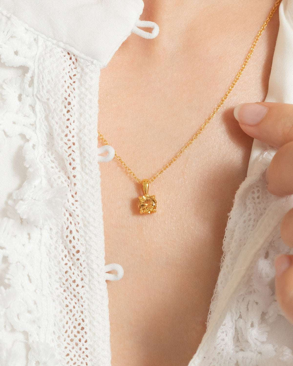 Citrine solitaire pendant necklace on a gold chain with a faceted round gemstone