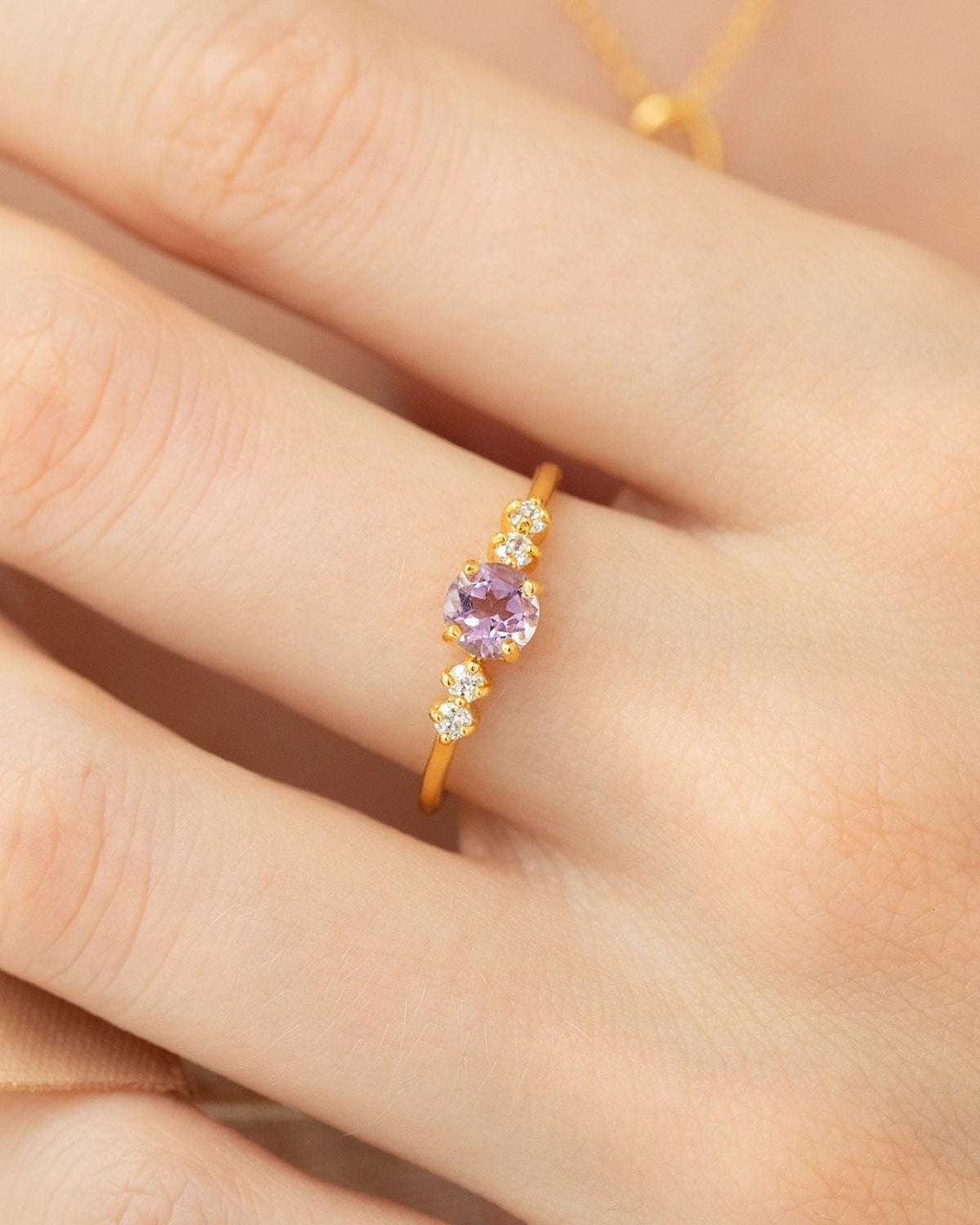 Gold vermeil five-stone amethyst ring with lavender center and tiny clear stones on finger