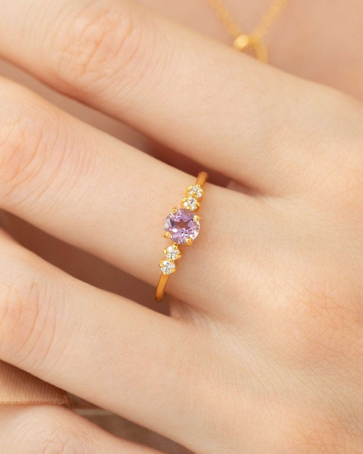 Gold vermeil five-stone amethyst ring with lavender center and tiny clear stones on finger