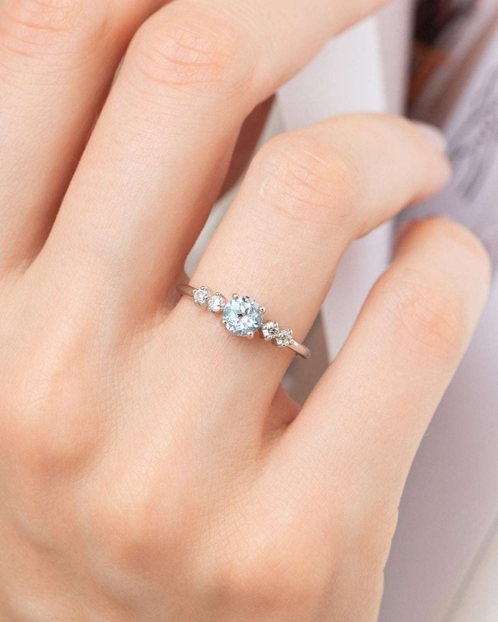 Sterling silver ring with three small blue topaz stones on finger