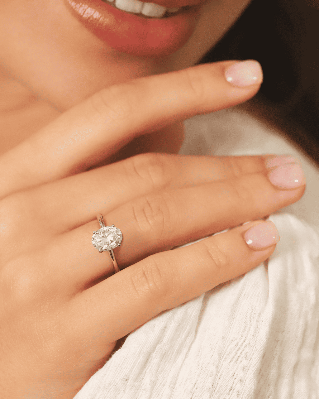 Sterling silver oval solitaire engagement ring on hand, close-up of oval moissanite stone