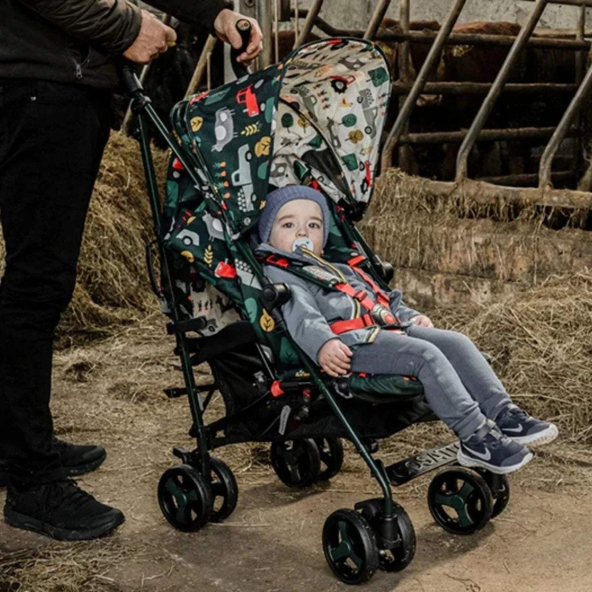 Infant in printed stroller with canopy and seat harness, sitting in reclined position