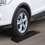 Black plastic car ramp under front wheel with textured grid anti-slip tread