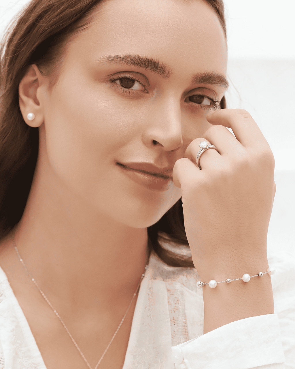 Freshwater pearl bracelet with small round pearls and silver chain links, worn on wrist.