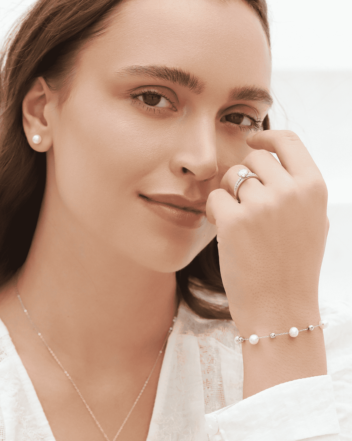 Freshwater pearl bracelet with small round pearls and silver chain links, worn on wrist.