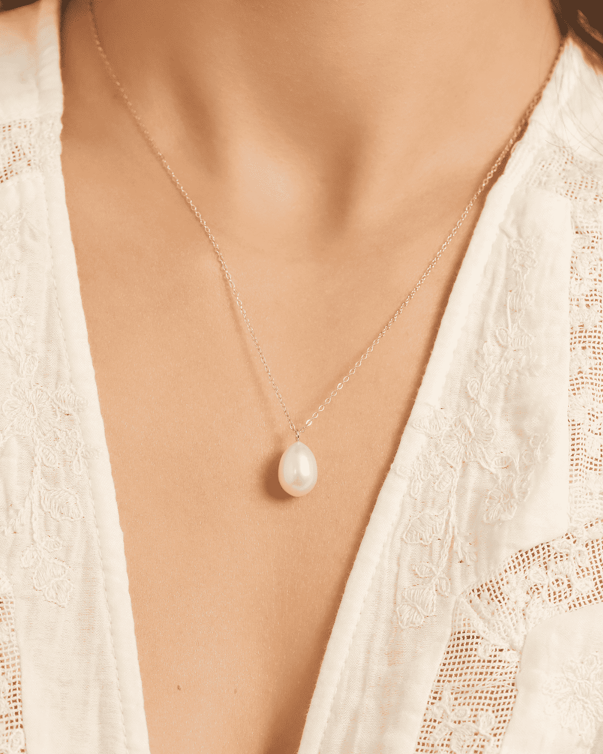 Sterling silver teardrop freshwater pearl pendant necklace resting on neckline