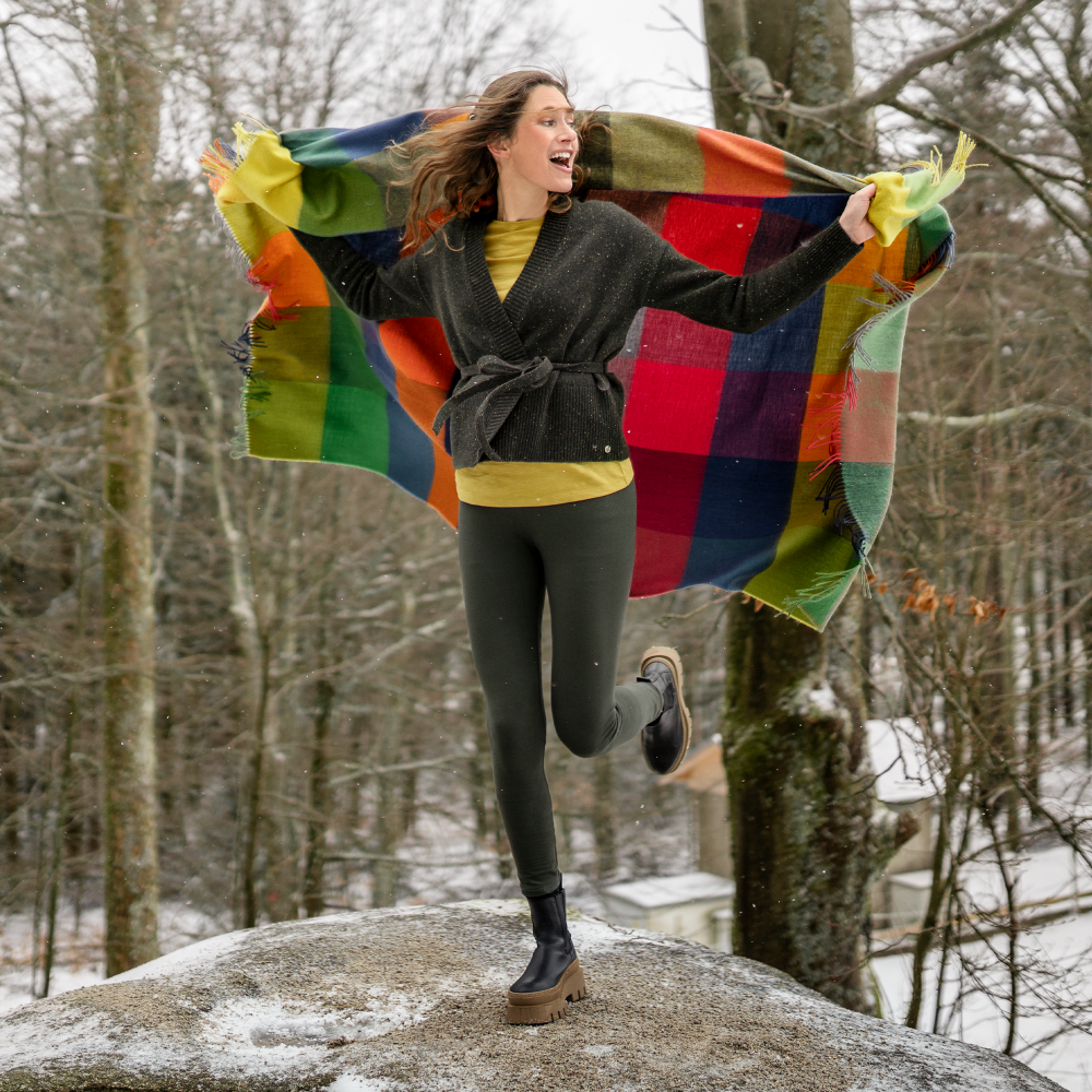 Person jumping in the air with a colorful blanket in a snowy forest