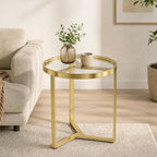 Gold round side table with clear glass top and geometric metal frame for small spaces