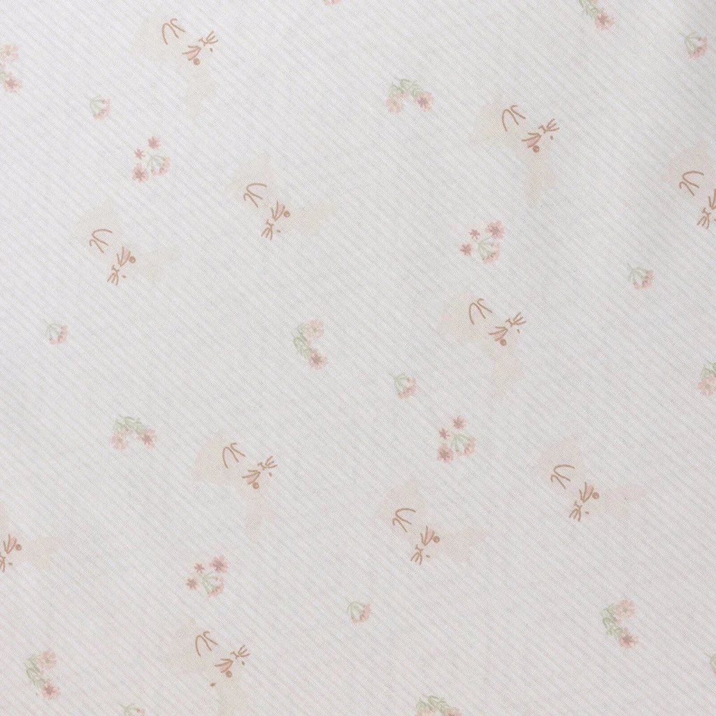 White baby sheet close-up with fine texture and small pastel floral print