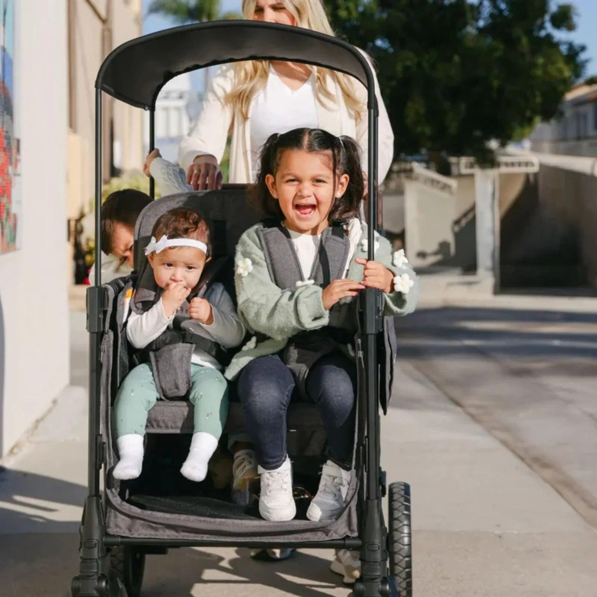 Jet black stroller wagon with canopy and front view of two children