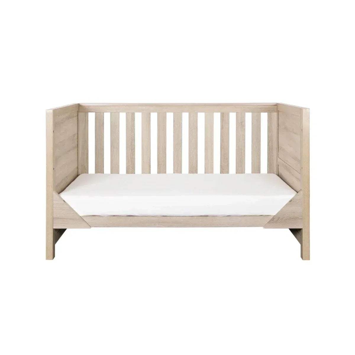 Oak cot bed with solid end panels, vertical slat headboard and footboard, and mattress platform