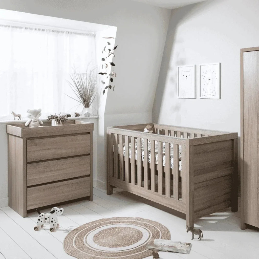 Oak changing unit in nursery corner with three-drawer cabinet and side rail.