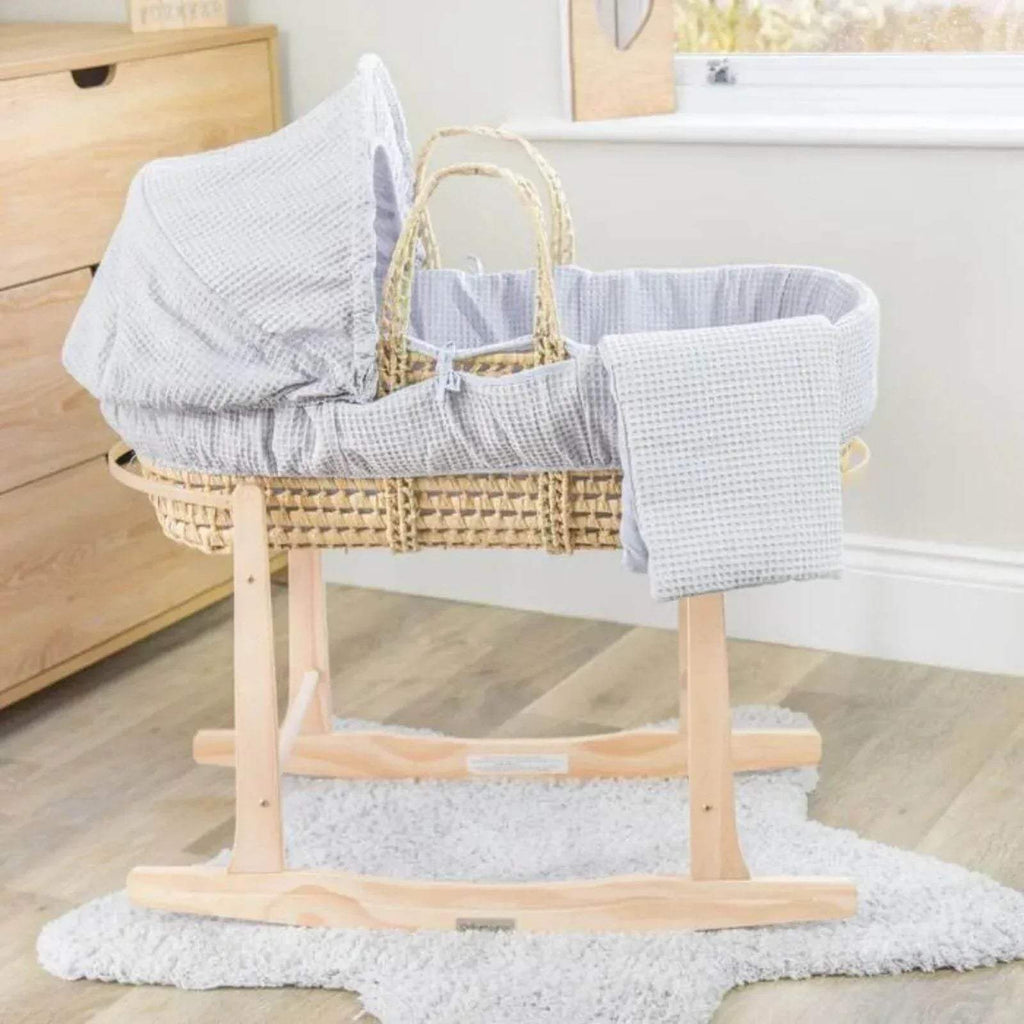 Wooden rocking stand holding a woven basket with gray fabric blanket
