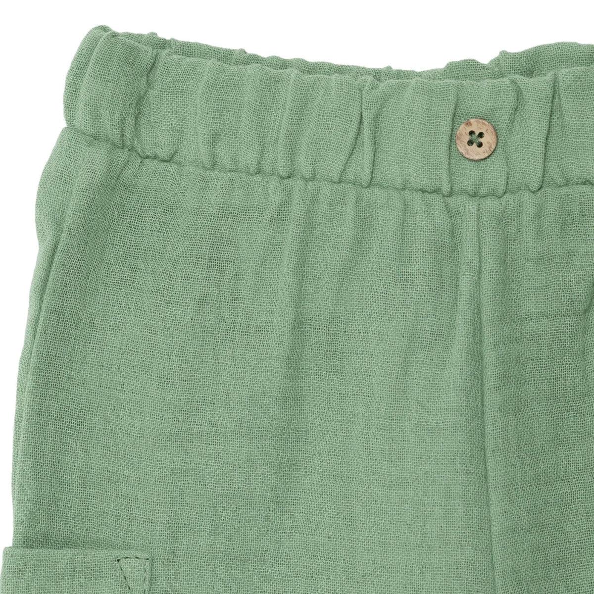 Green muslin baby shorts close-up of elastic waistband with wooden-look button