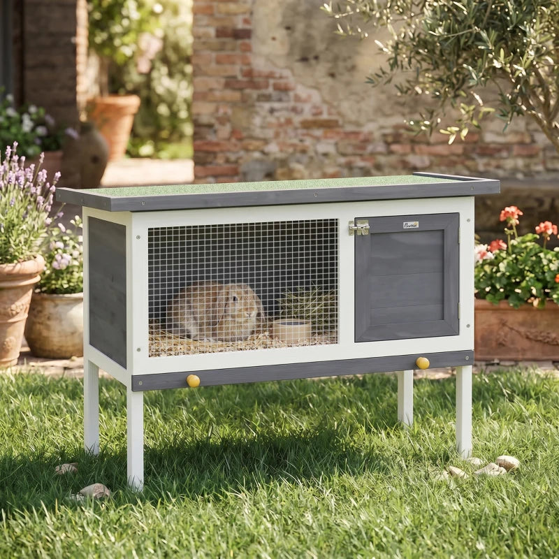 Grey wooden rabbit hutch with wire front and dark side door, raised on legs