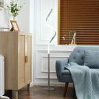 Silver spiral LED floor lamp with wavy stem and square base beside seating