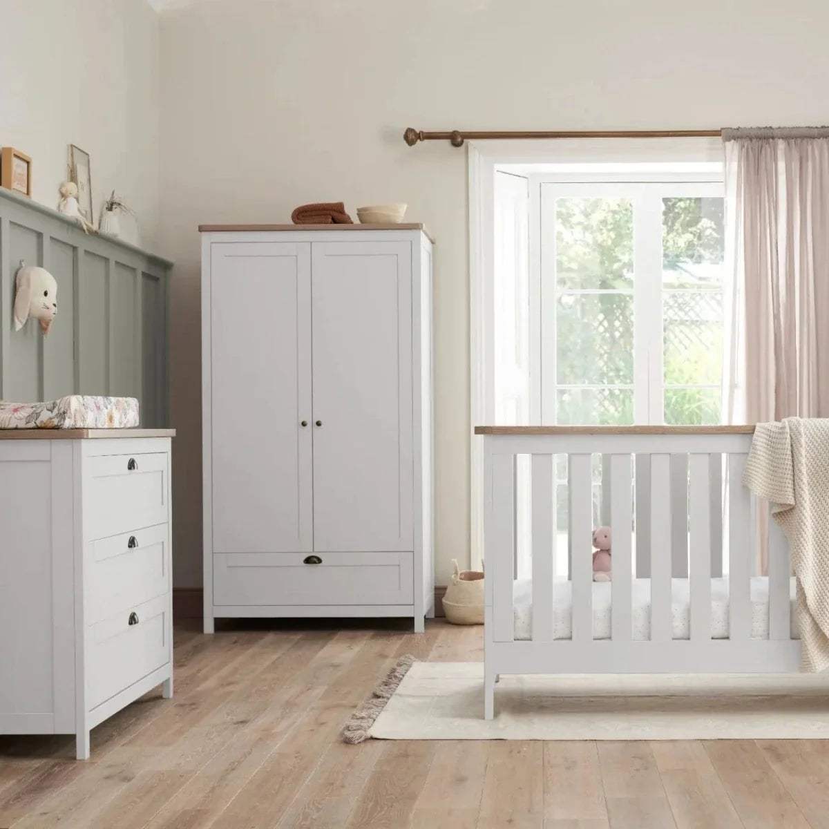White wardrobe with double doors and a white toddler cot with vertical guard rails