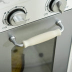 White toy kitchen with front oven control knobs and a cream-colored oven handle