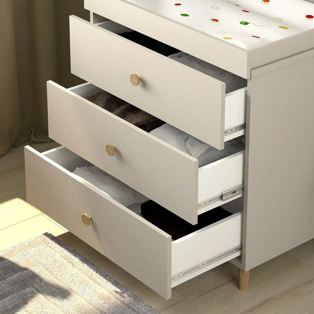 Kids changing dresser with drawers open, showing dark interior shelves and brass knob pulls