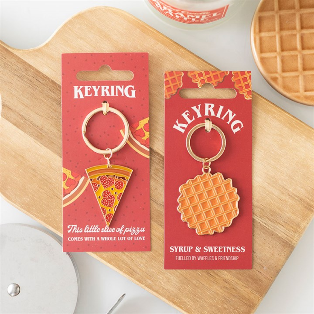 Two keychains in packaging on a wooden board with waffles in the background
