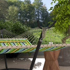 Black hammock stand holding a striped hammock between curved end hooks