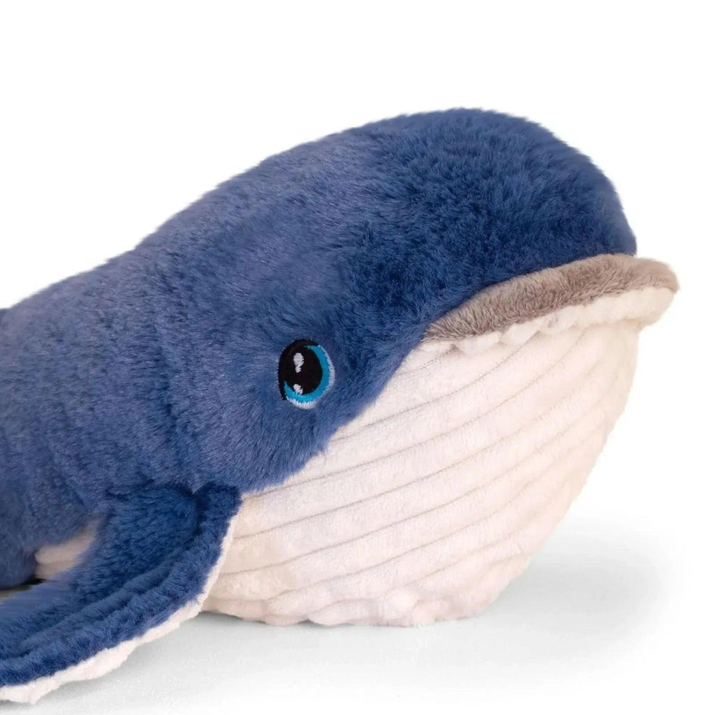 Blue plush whale close-up with big embroidered eye and white underside belly