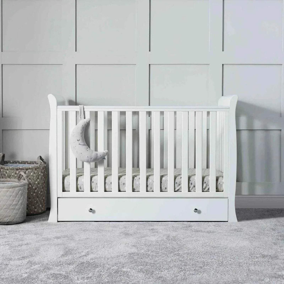 White baby crib with slatted rails and drawer front panel