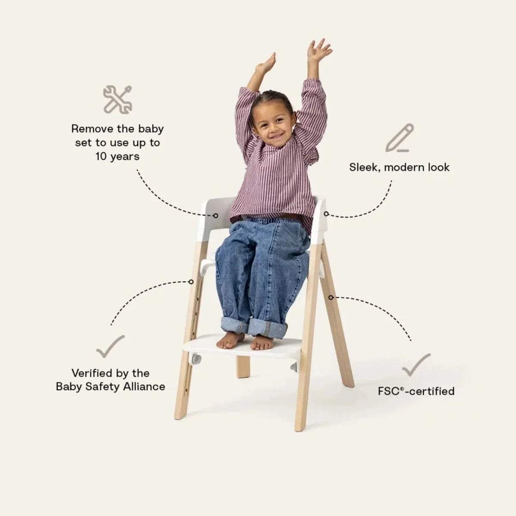 Black highchair with warm brown legs; child seated and raising arms