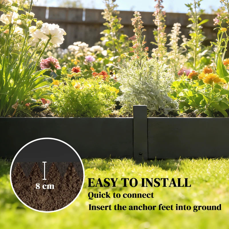 Black metal garden fence edging with short pickets in flower bed.
