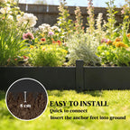 Black metal garden fence edging with short pickets in flower bed.