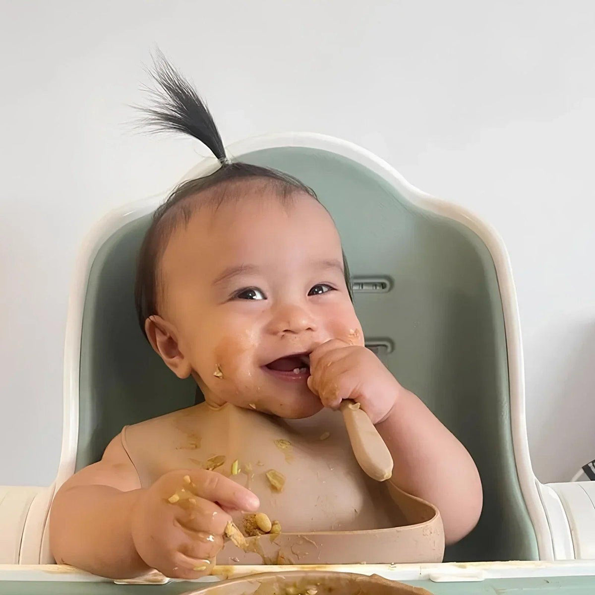 Dusky blue silicone baby bib with front pocket, catching crumbs during feeding
