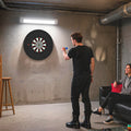 Black bristle dartboard mounted on an indoor wall for play