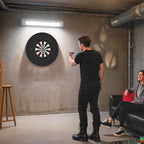 Black bristle dartboard mounted on an indoor wall for play