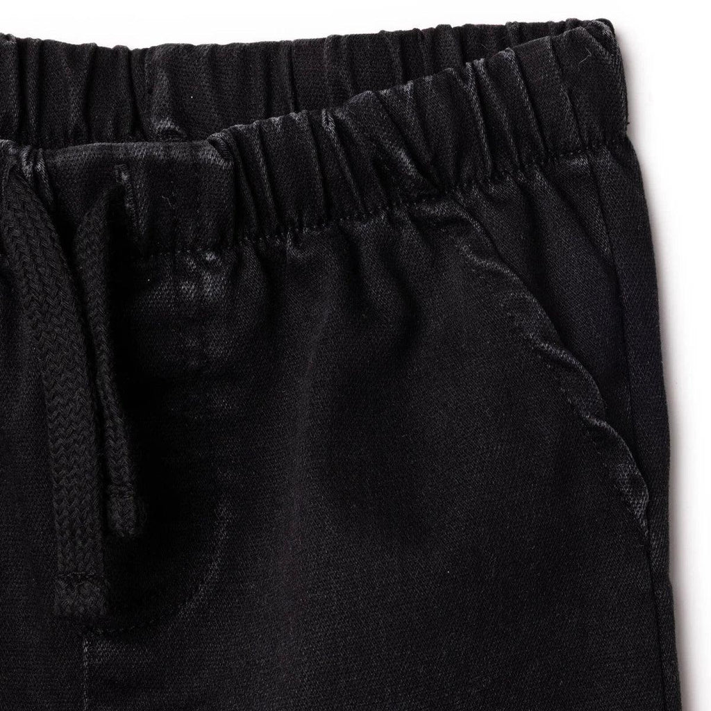 Black denim trousers close-up: front pocket detail and fly stitching