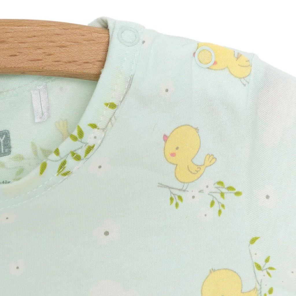 Light blue baby romper chest close-up with yellow chick graphic and snap button at shoulder
