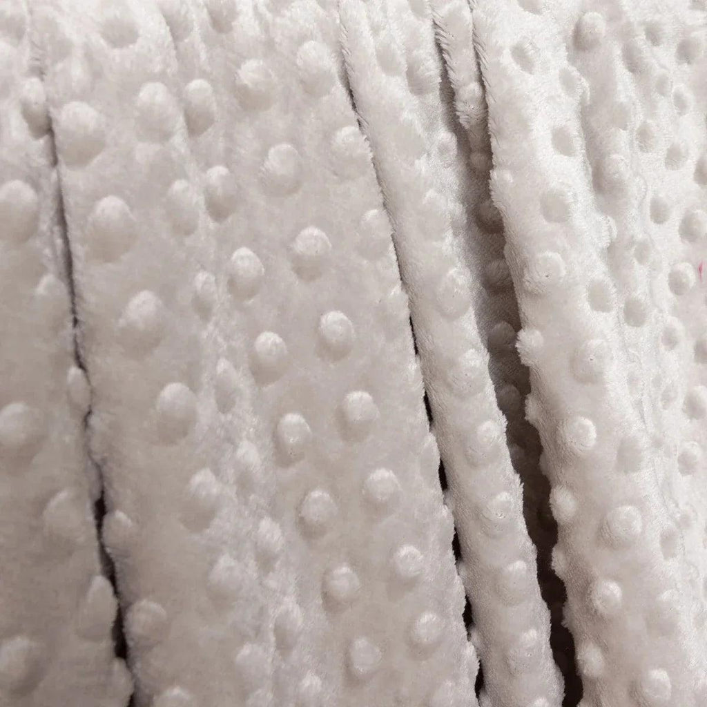 Close-up of beige fleece baby blanket with raised dot pattern and seam detail