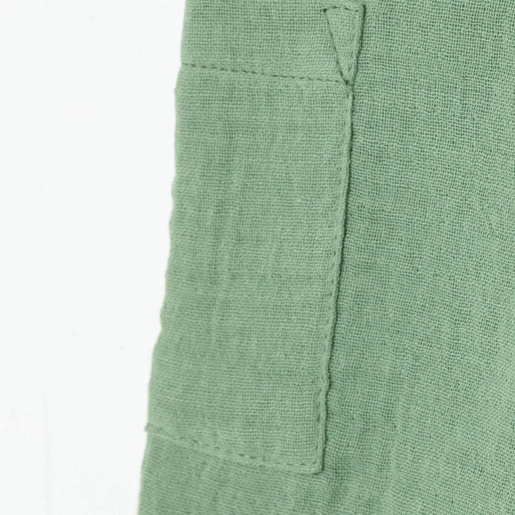 Green muslin baby shorts side view with patch pocket seam detail