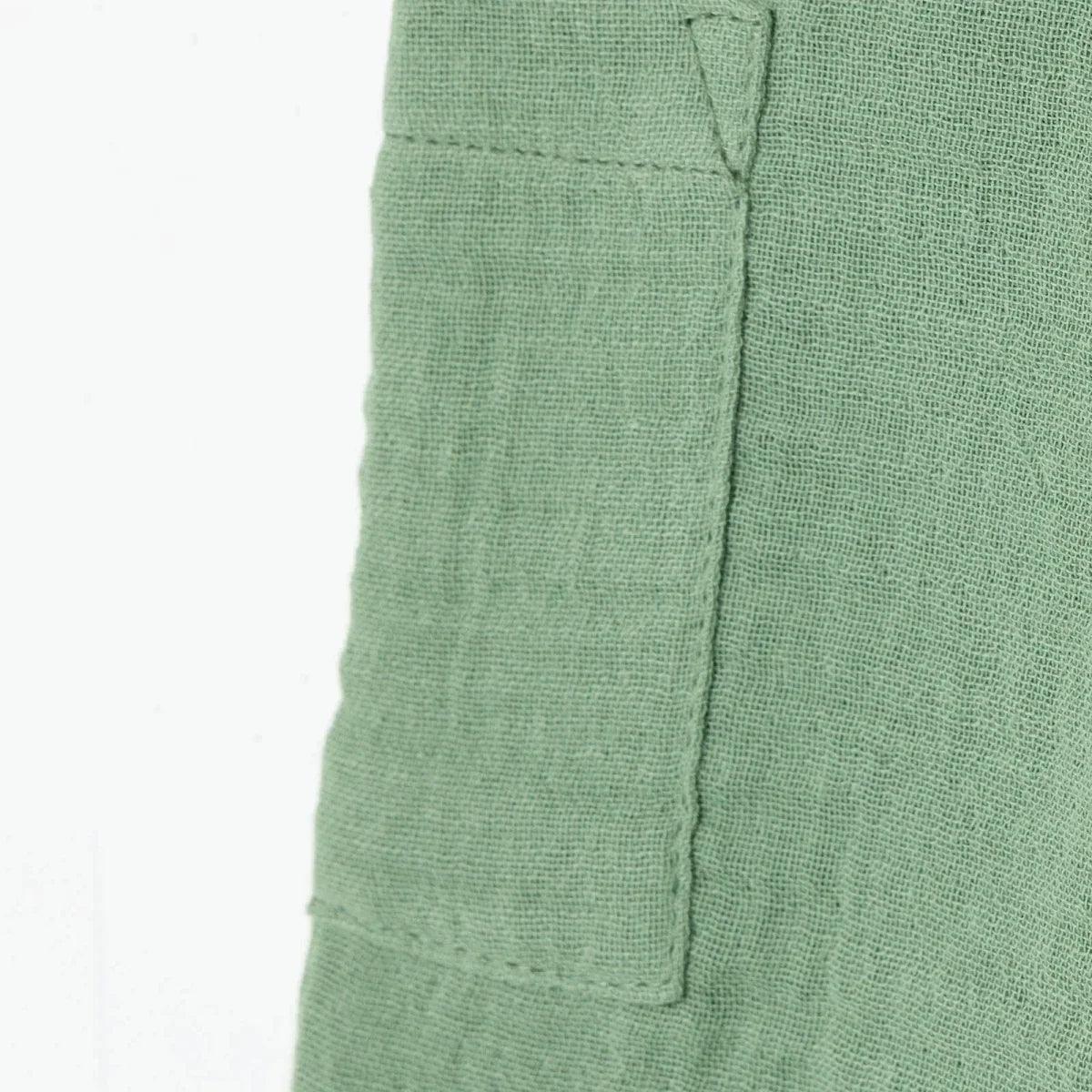 Green muslin baby shorts side view with patch pocket seam detail