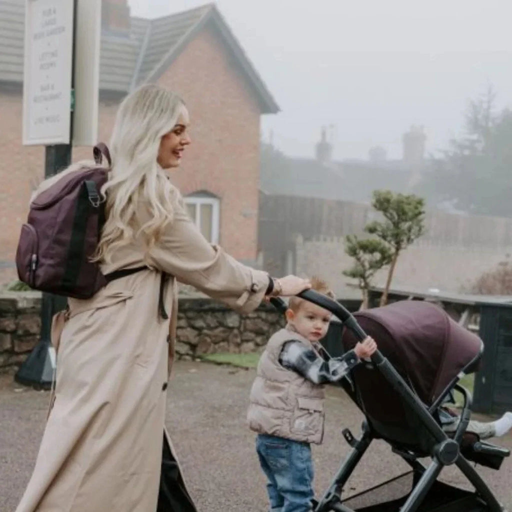 Single stroller with black seat and wheels, outdoors near a building path