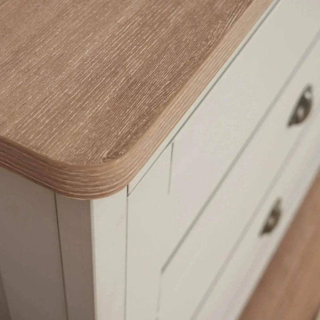 Oak-finish top on a white chest changer with rounded corner and metal handle