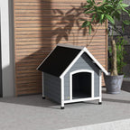 Grey wooden dog kennel with black roof and arched entrance, outdoor patio