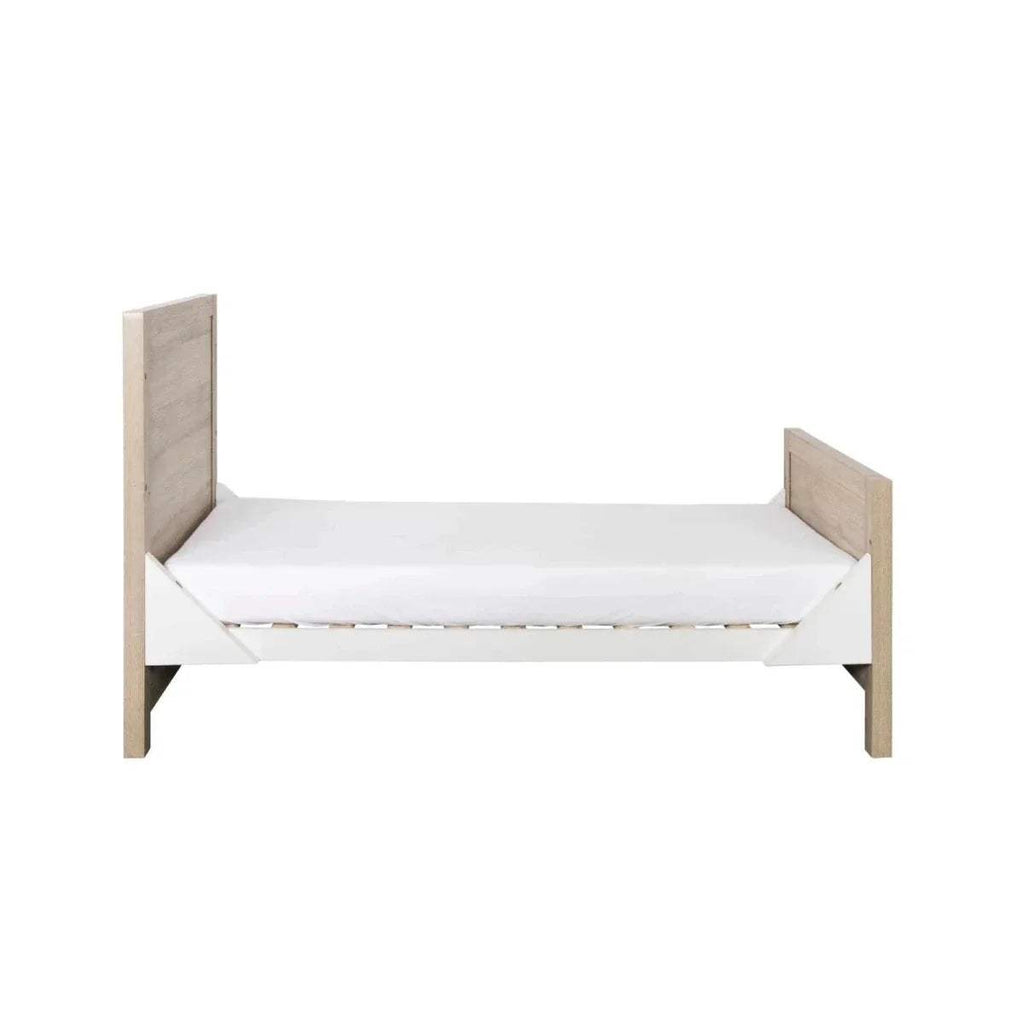 White mattress on light oak junior bed frame with solid side panels