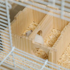 Hamster inside a white wire cage with wooden hide hut and bedding