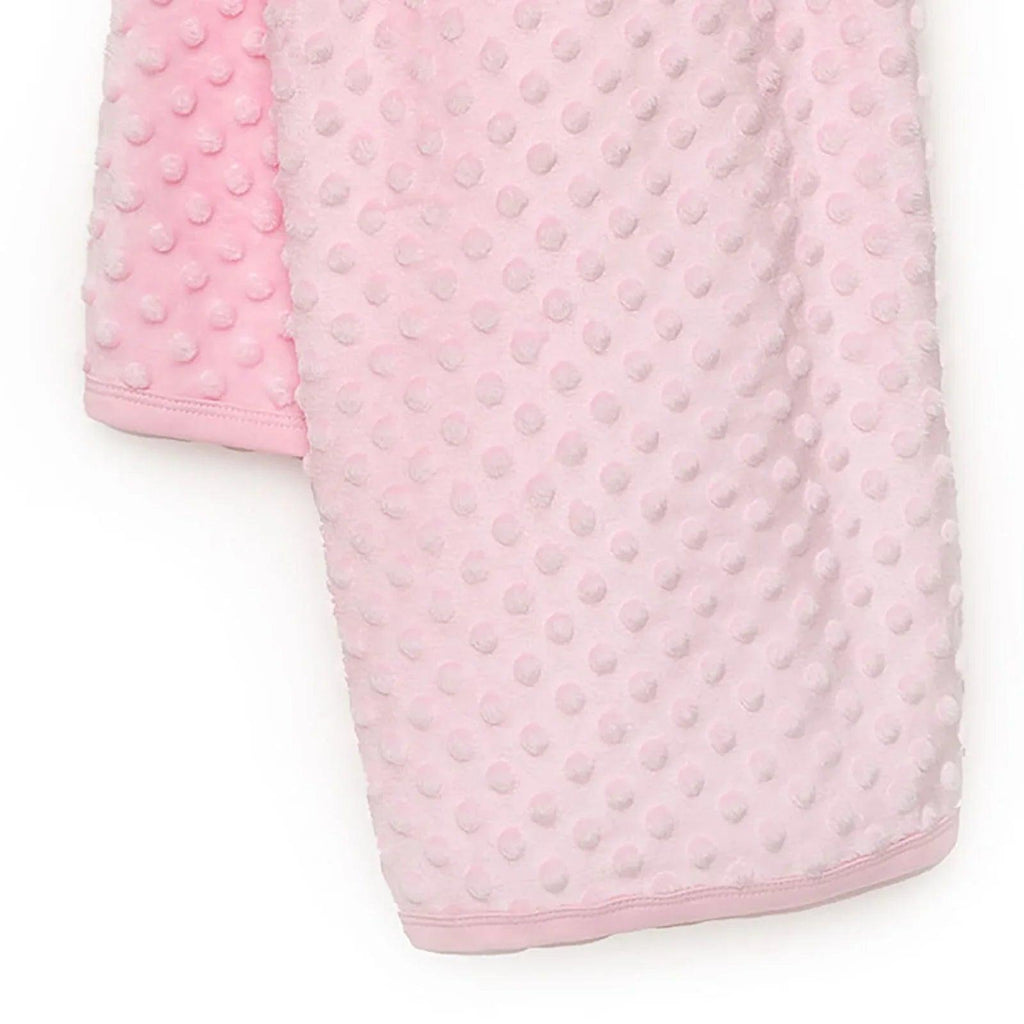 Pink baby fleece blanket folded, showing raised dot texture and stitched hem.