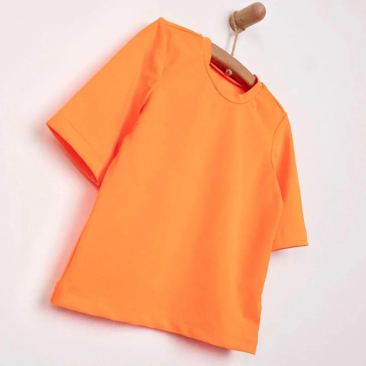 Neon orange short sleeve baby swim top on wooden hanger, angled view.