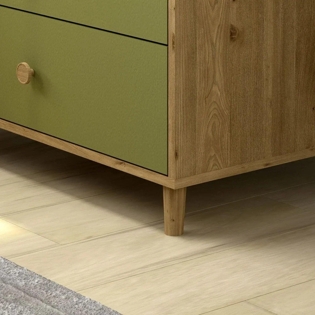 Close-up of pistachio green drawer front and light wood legs on changing dresser