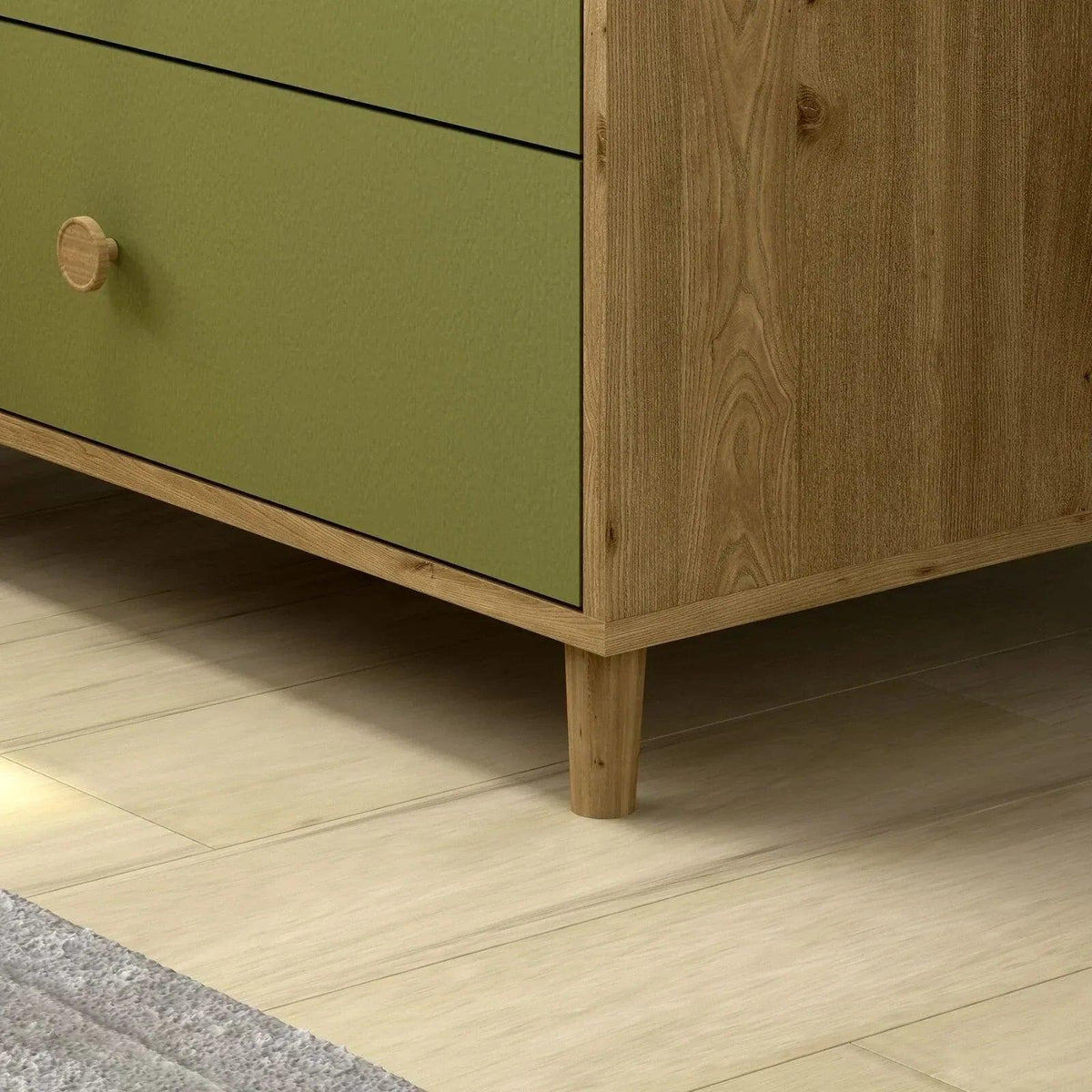 Close-up of pistachio green drawer front and light wood legs on changing dresser