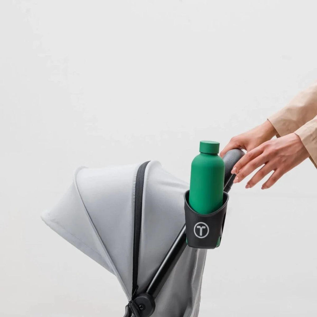 Black cup holder holding a green water bottle on stroller handle