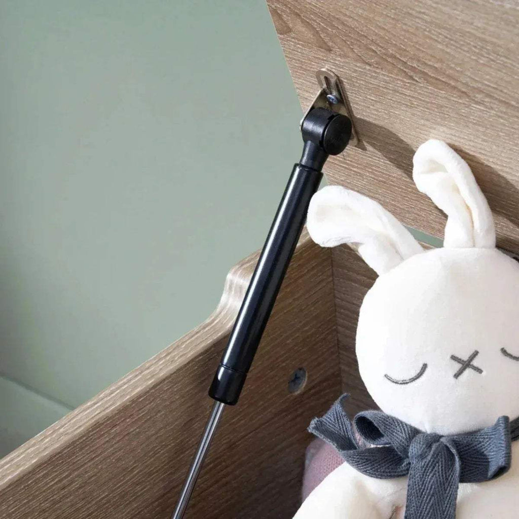 Oak toy box corner with black hinge rod and plush rabbit beside